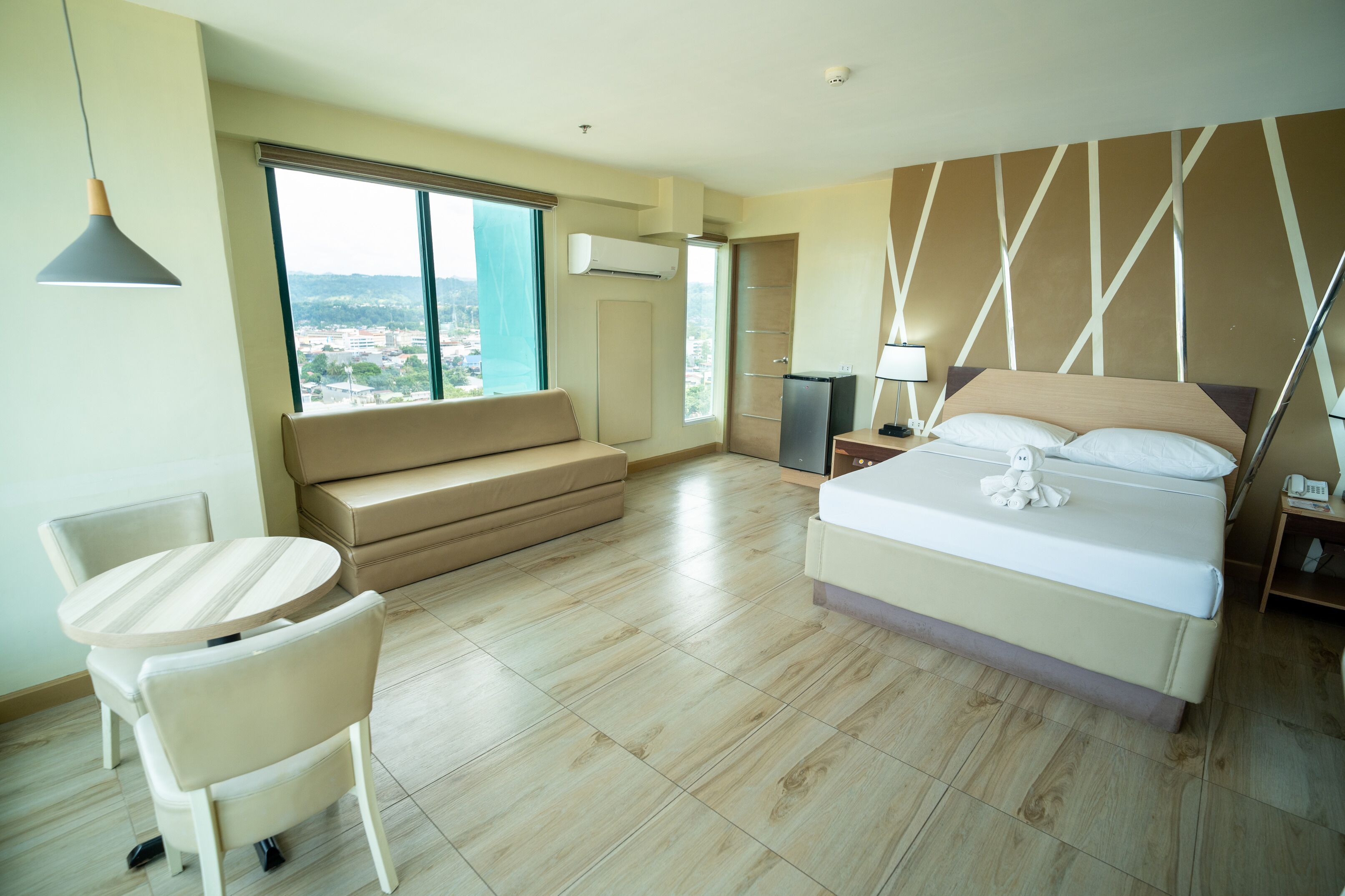 Una habitación de hotel moderna con una cama grande, un sofá, una mesa de comedor y un televisor.