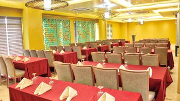 A conference room with multiple tables and chairs, red tablecloths, and a decorative ceiling design.