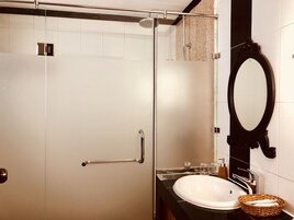 Un bagno con cabina doccia in vetro, un lavandino bianco e uno specchio con cornice nera.