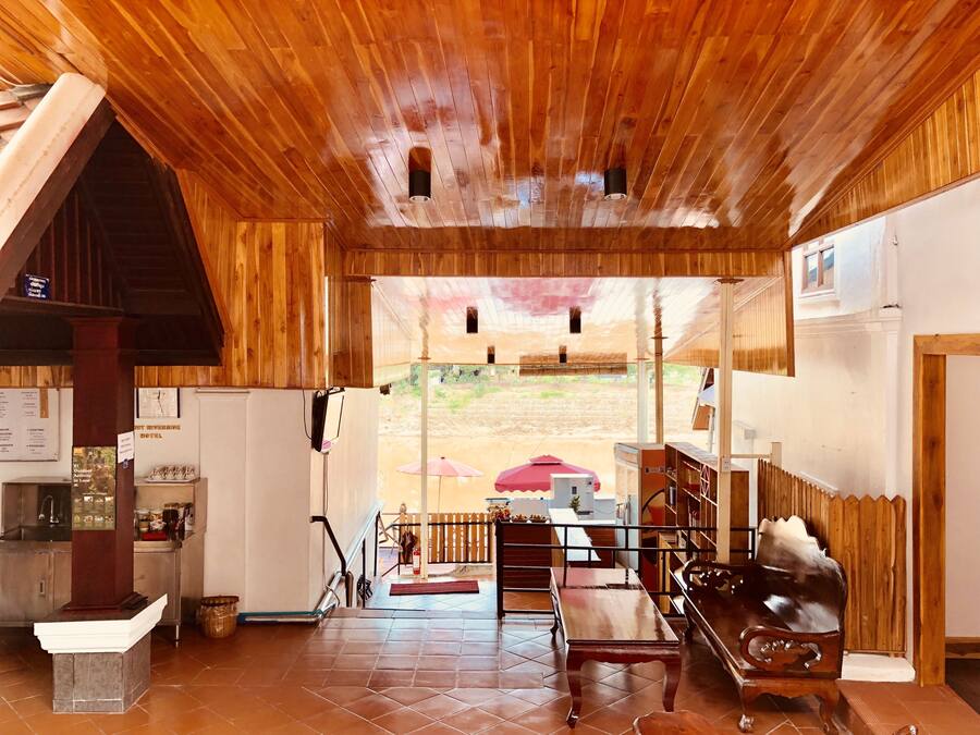 A wooden interior with a view to the outside, a reception desk, and a seating area with a bench and table.