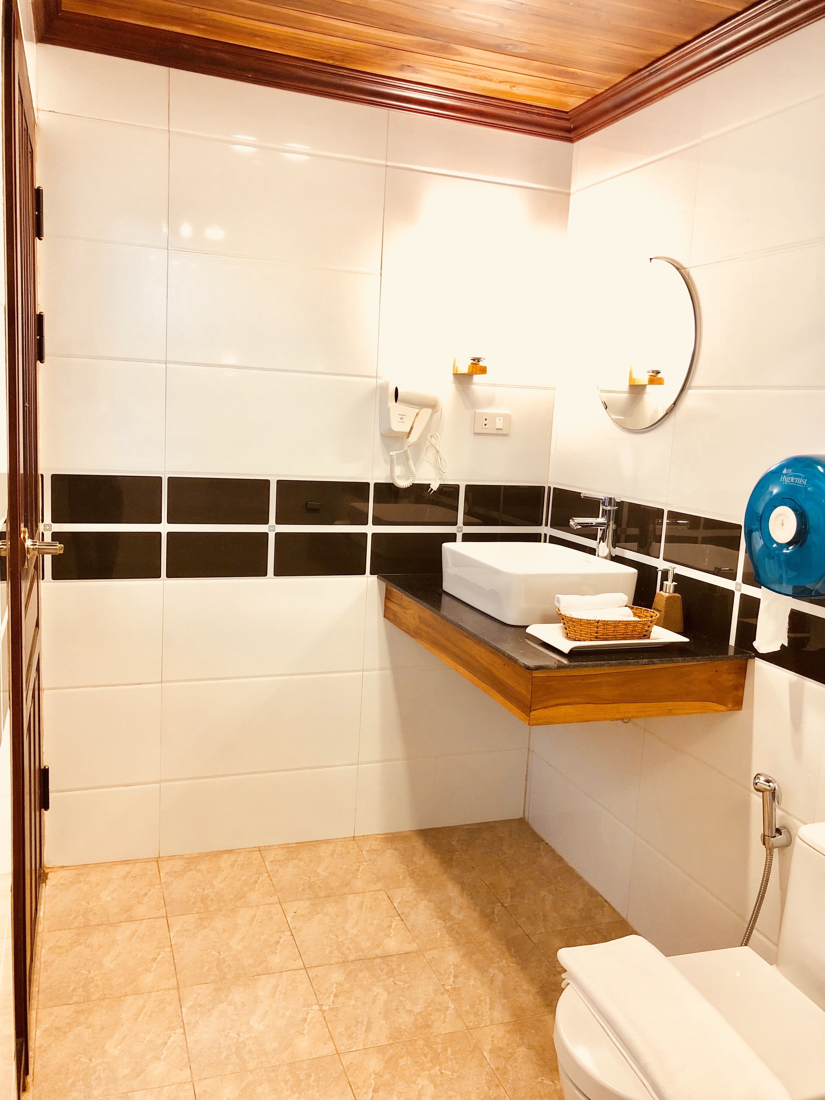 A bathroom with a white toilet, a sink with a wooden countertop, a mirror, and a towel rack.