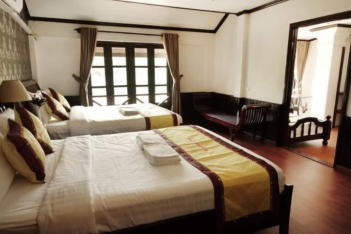A hotel room with two beds, a sitting area, and a view of the outdoors.