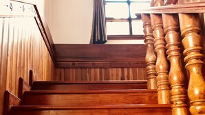 A wooden staircase with a handrail and a window with curtains. - Merry Riverside Hotel (Luang Prabang)