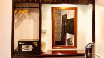Une petite chambre équipée d’un réfrigérateur, d’une petite table, d’un miroir et d’un radiateur.