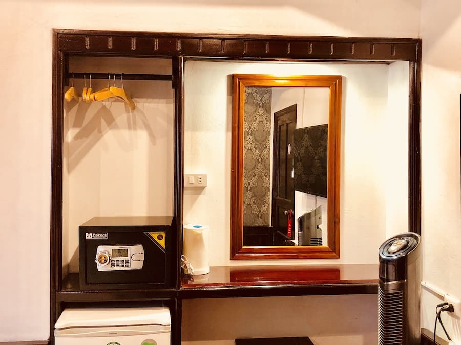 Une petite chambre équipée d’un réfrigérateur, d’une petite table, d’un miroir et d’un radiateur.