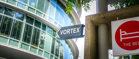 A modern building with a glass facade and a sign pointing to "VORTEX".