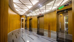 A modern elevator lobby with a geometric ceiling design, polished marble floors, and wooden panel walls. - The VIEW at Vortex KLCC (Kuala Lumpur)