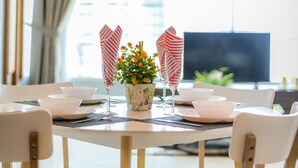 A dining area with a round table, white chairs, a vase with flowers, and a television in the background. - The VIEW at Vortex KLCC (Kuala Lumpur)