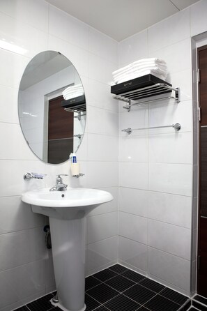 A bathroom with a white sink, a mirror, a towel rack, and a shower area.