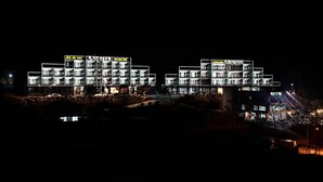 Un hotel con varios pisos y balcones, iluminado por la noche.