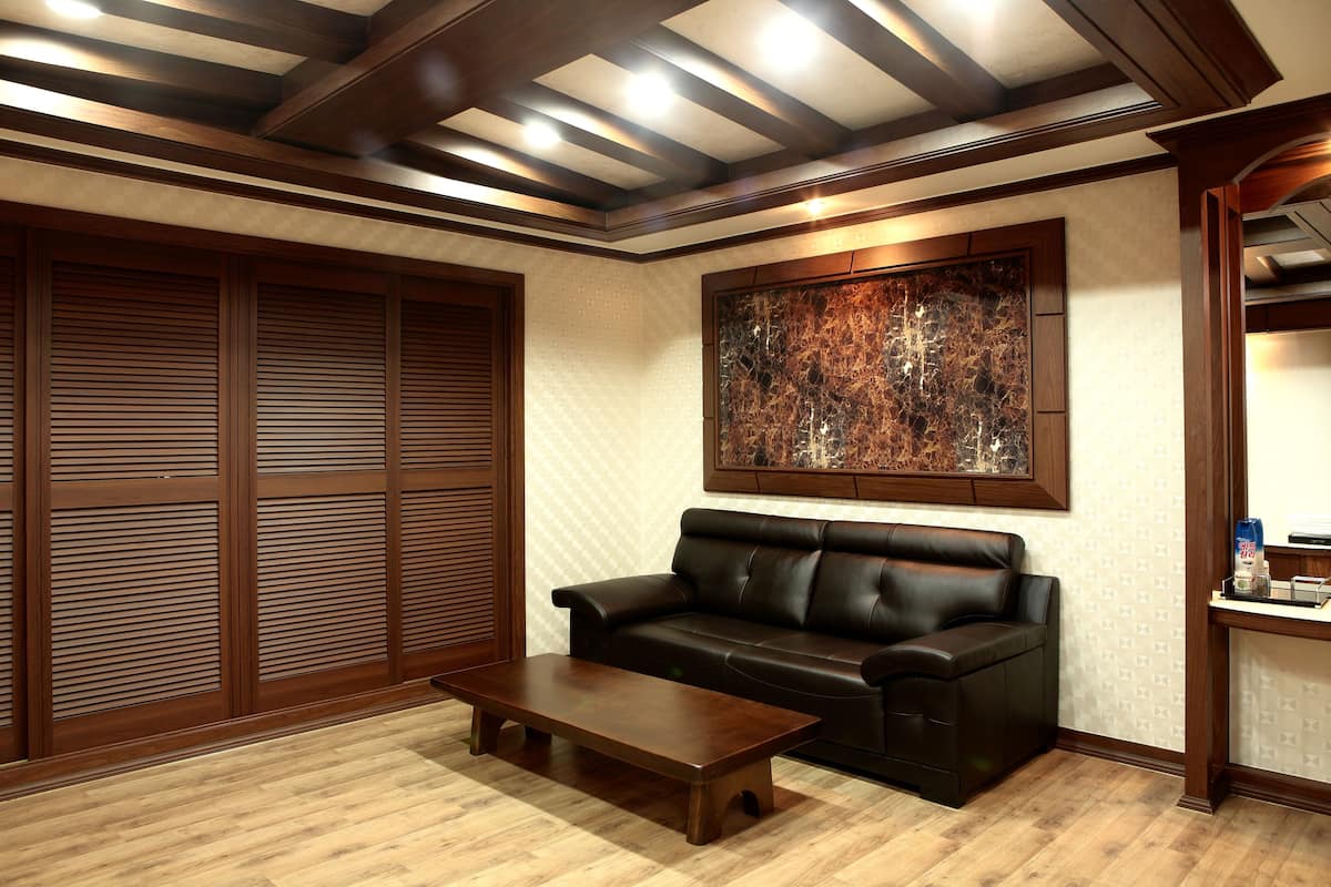 A room with a dark leather sofa, a wooden coffee table, and a large abstract painting on the wall.