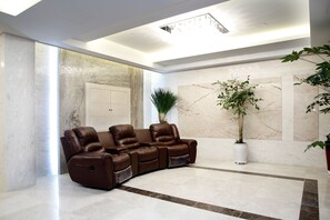 A modern living room with a leather sofa, marble walls, and a large potted plant. - Ritz Castle Resort (Taean)