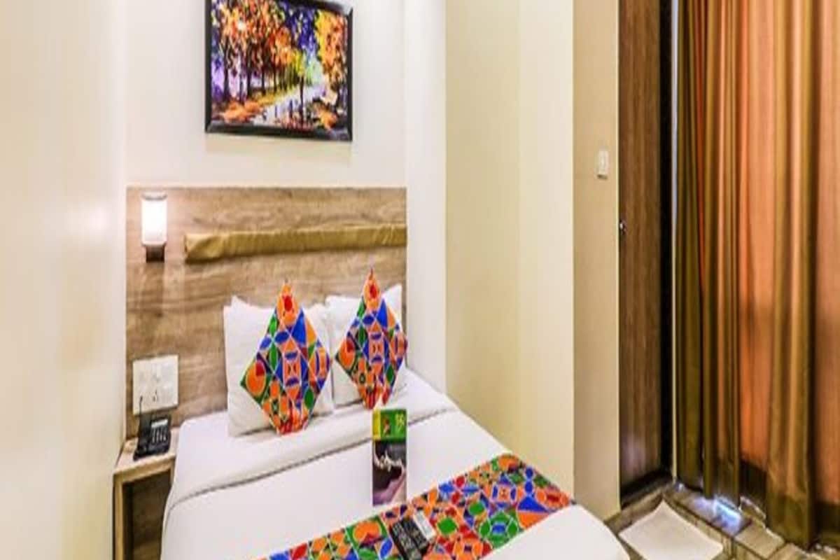 Une chambre d’hôtel avec un lit, une table de chevet, un tableau, un appareil de climatisation et une porte avec des rideaux.