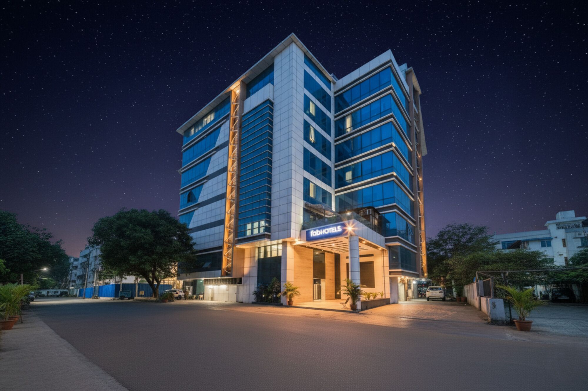 A modern hotel building with a prominent 'FabHotels' sign, featuring a multi-story structure with large windows and a well-lit entrance.