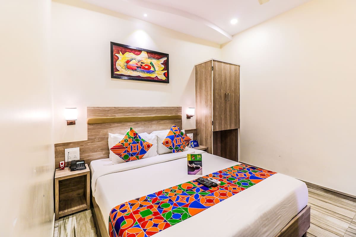 Une chambre d’hôtel avec un lit, une table de chevet, une armoire et un tableau au mur.