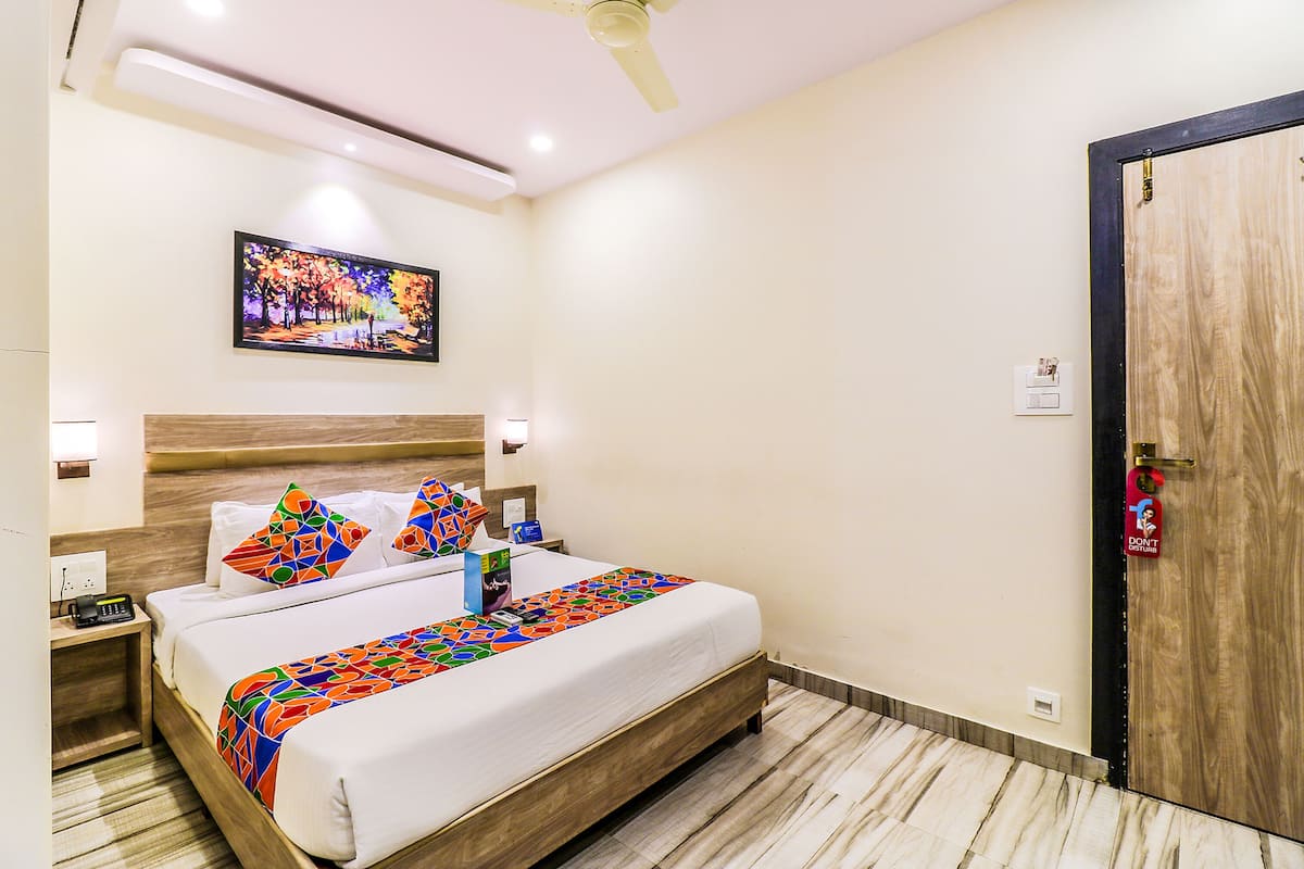 Une chambre d’hôtel avec un lit, une table de chevet, une commode et un tableau au mur.