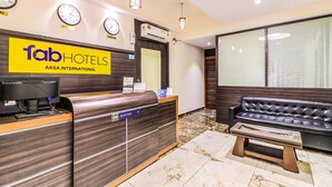 Un espace d’accueil d’hôtel comprenant un comptoir de réception, un canapé et un banc.