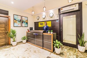 Mostrador de recepción de hotel con una recepcionista, un reloj y un cartel que dice "fab hotels".