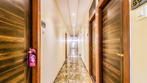 Un couloir d’hôtel avec des portes en bois, un sol en marbre et une pancarte « Ne pas déranger ».
