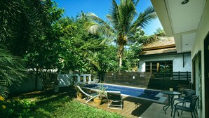 A backyard with a swimming pool, a wooden deck, and outdoor furniture. - Samui Villa Whitney (Koh Samui)