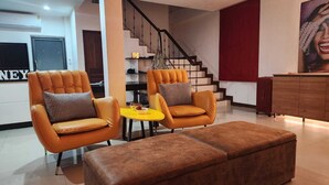 A modern living room with two leather armchairs, a small yellow table, and a brown ottoman. - Samui Villa Whitney (Koh Samui)
