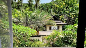 A view of a swimming pool with a tiled floor, surrounded by lush greenery and palm trees. - Samui Villa Whitney (Koh Samui)