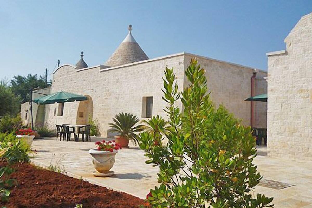 Un bâtiment en pierre surmonté d’un toit conique, doté d’une terrasse et agrémenté de plantes en pot.