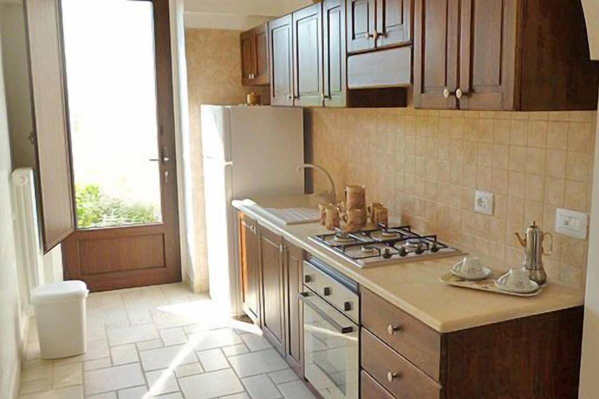 Une cuisine avec des meubles en bois, une cuisinière à gaz et un réfrigérateur blanc.