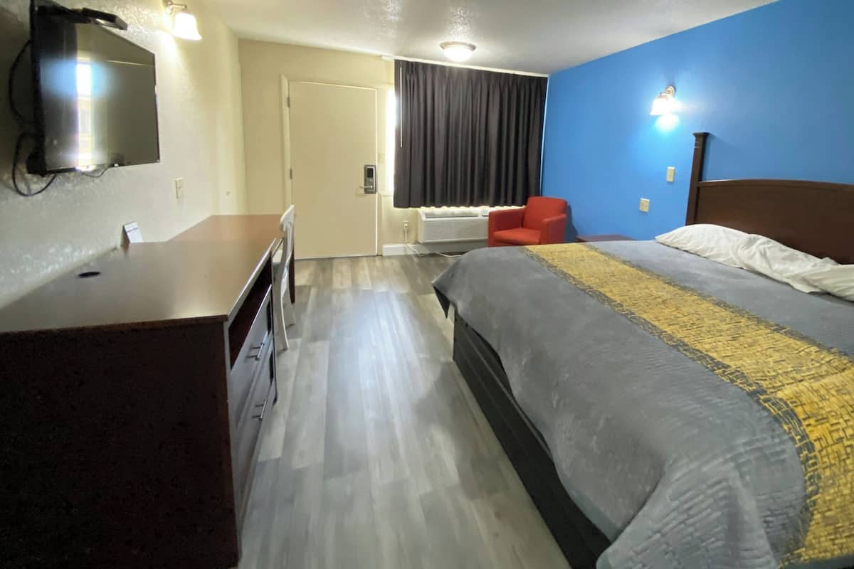 A hotel room with a bed, a desk, a chair, a television, and a window with curtains.