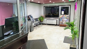 A reception area with a computer, ATM, chairs, a plant, and a magazine rack. - Express Inn Newport News (Newport News)