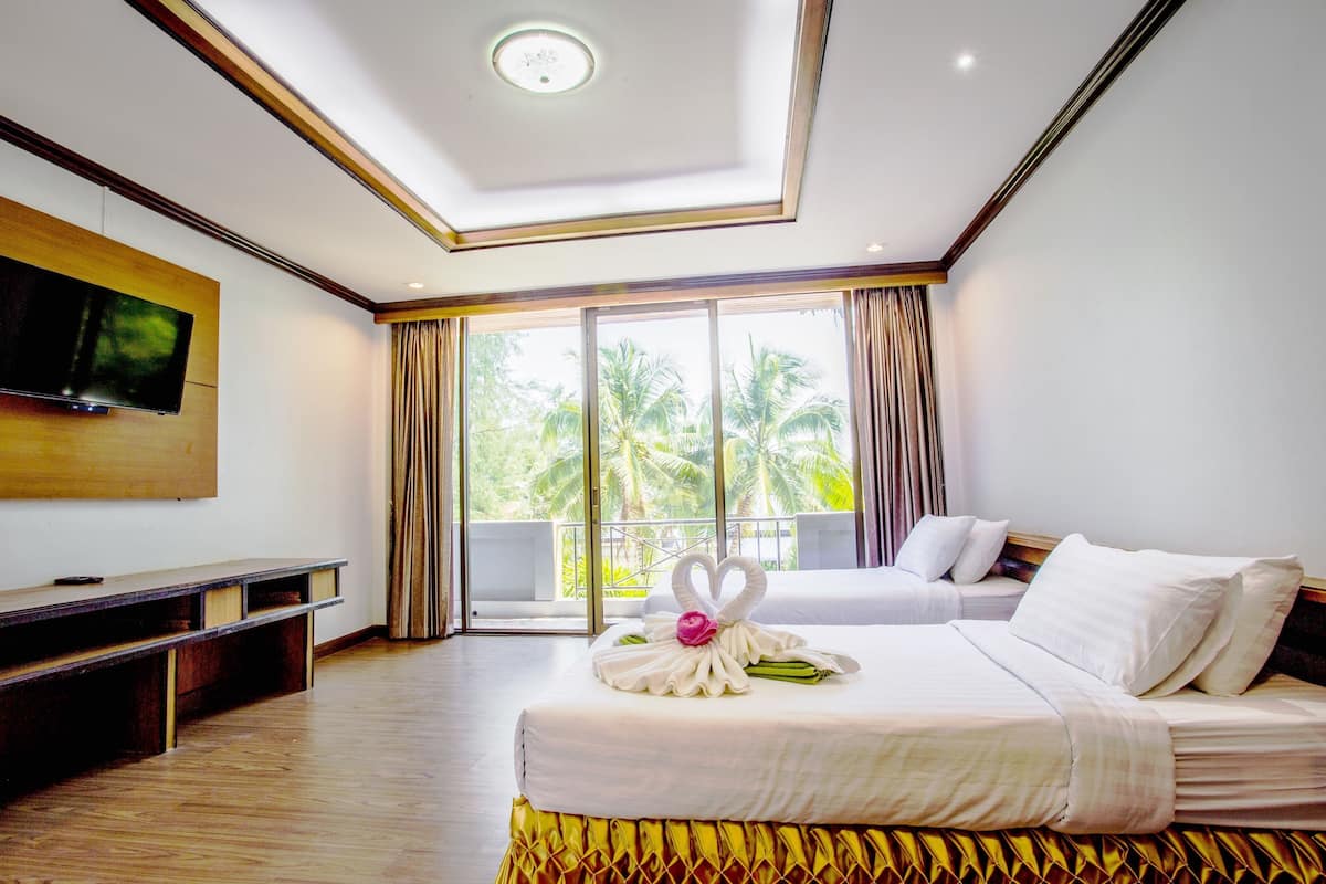 Una habitación de hotel con cama, televisión, balcón con cortinas e iluminación en el techo.
