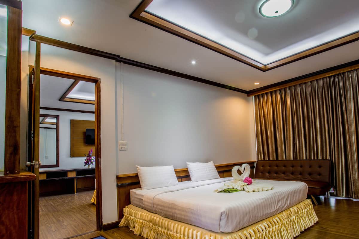 Una habitación de hotel con una cama grande, un tragaluz, un espejo y una cortina.