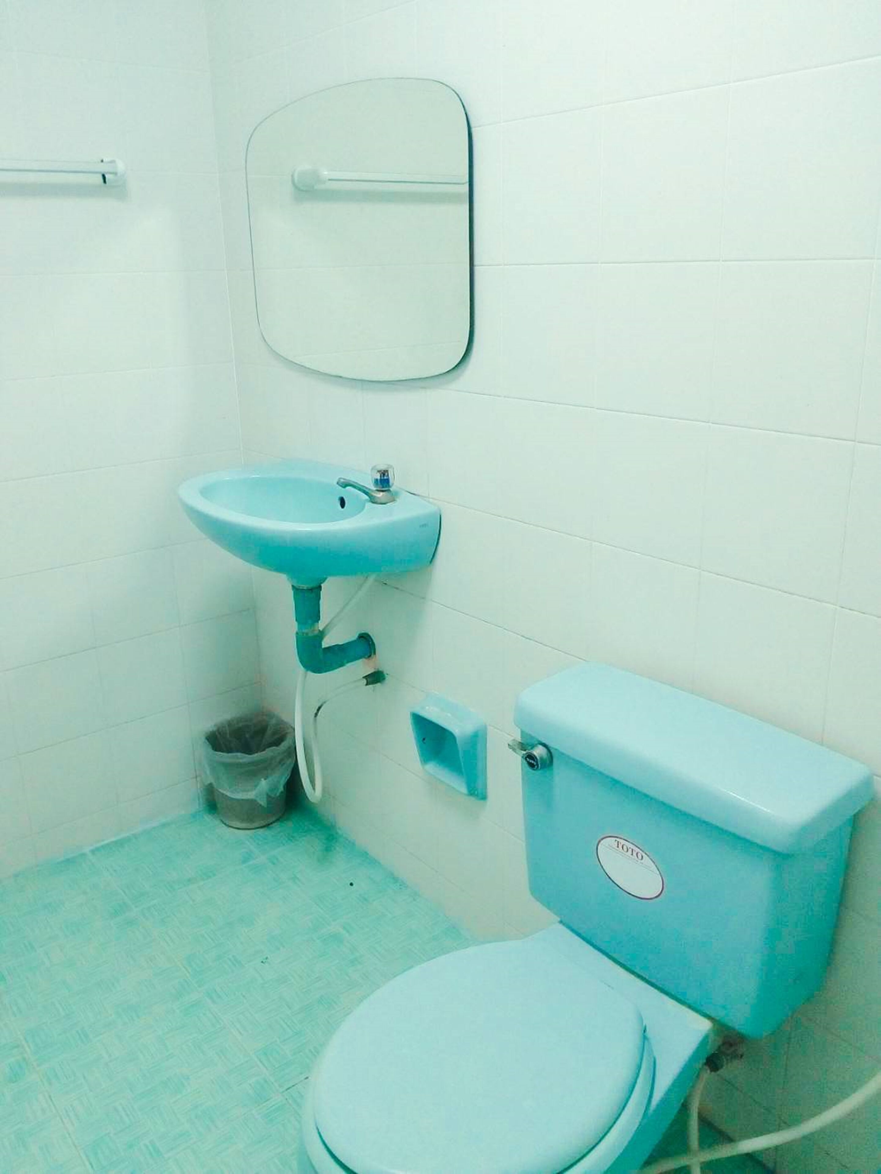 A bathroom with a toilet, sink, and mirror.