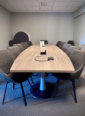 A conference room with a round table, grey upholstered chairs, and a blue base. - Kramfors Stadshotell (Kramfors)