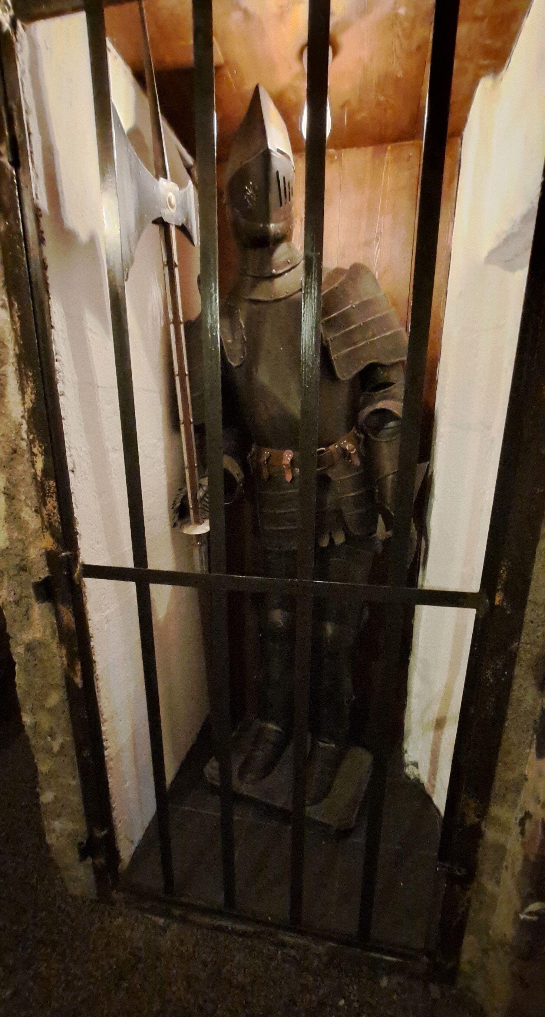 A medieval-style armored suit of armor inside a barred enclosure.