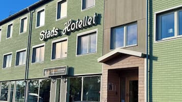 En byggnad med flera våningar, med en skylt som visar texten ”Stads Hotellet” och en skylt för ett gym under.