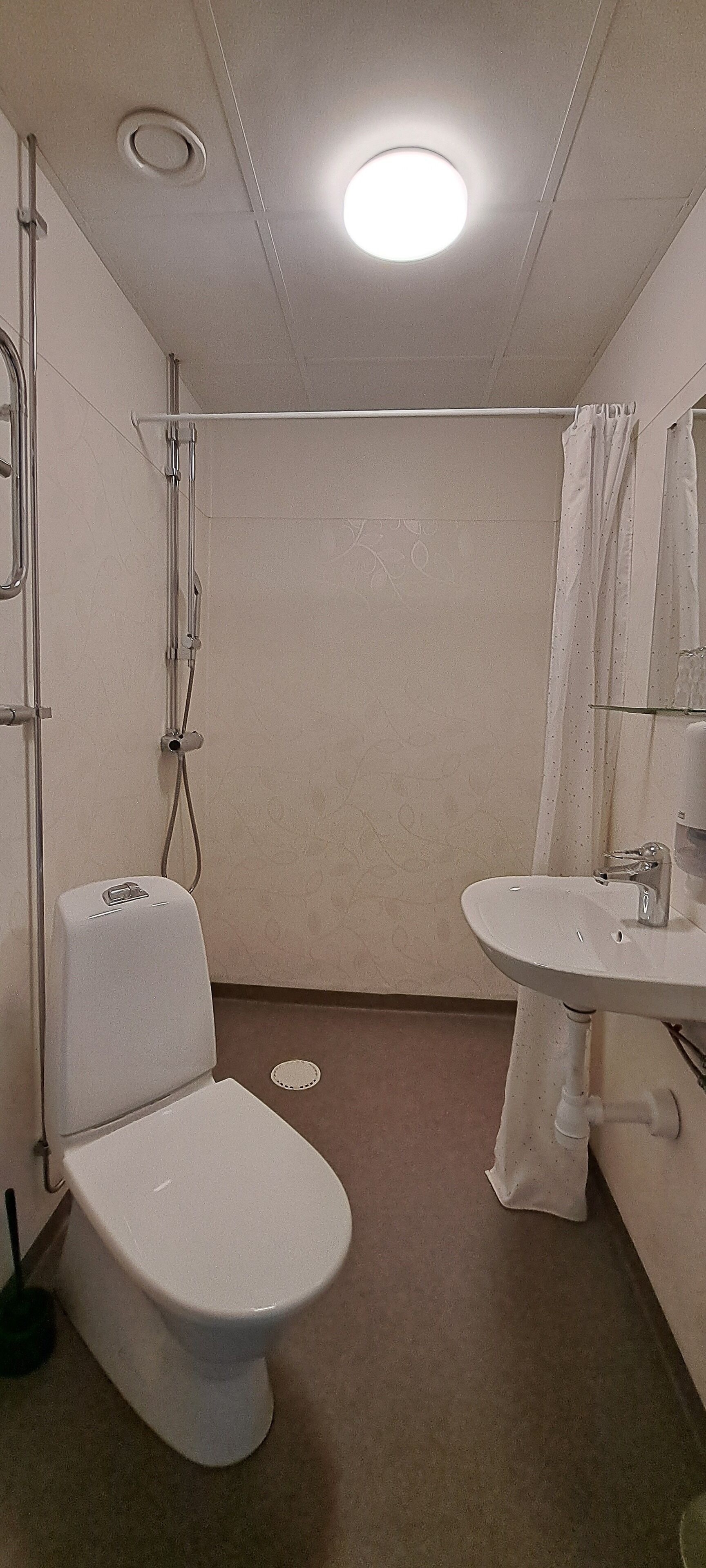 A small, compact bathroom with a toilet, sink, and shower.