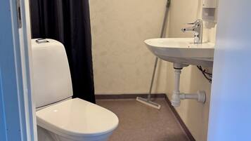 Een badkamer met toilet, wastafel en een dweil.