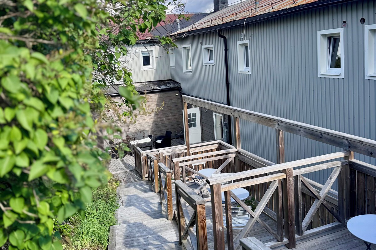 A wooden deck leading to a building with multiple windows and a metal roof.
