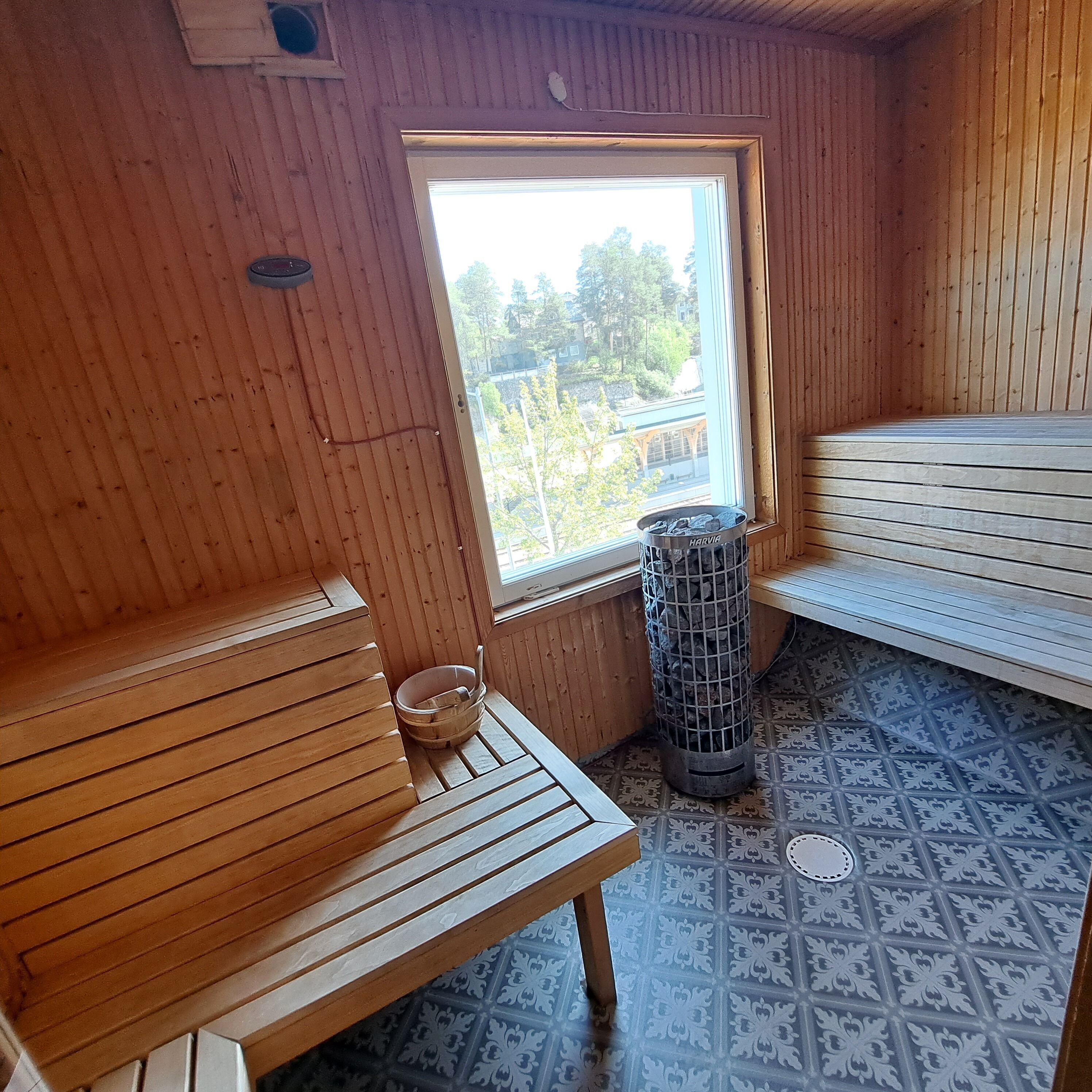Un sauna de madera con bancos y un ventanal grande.