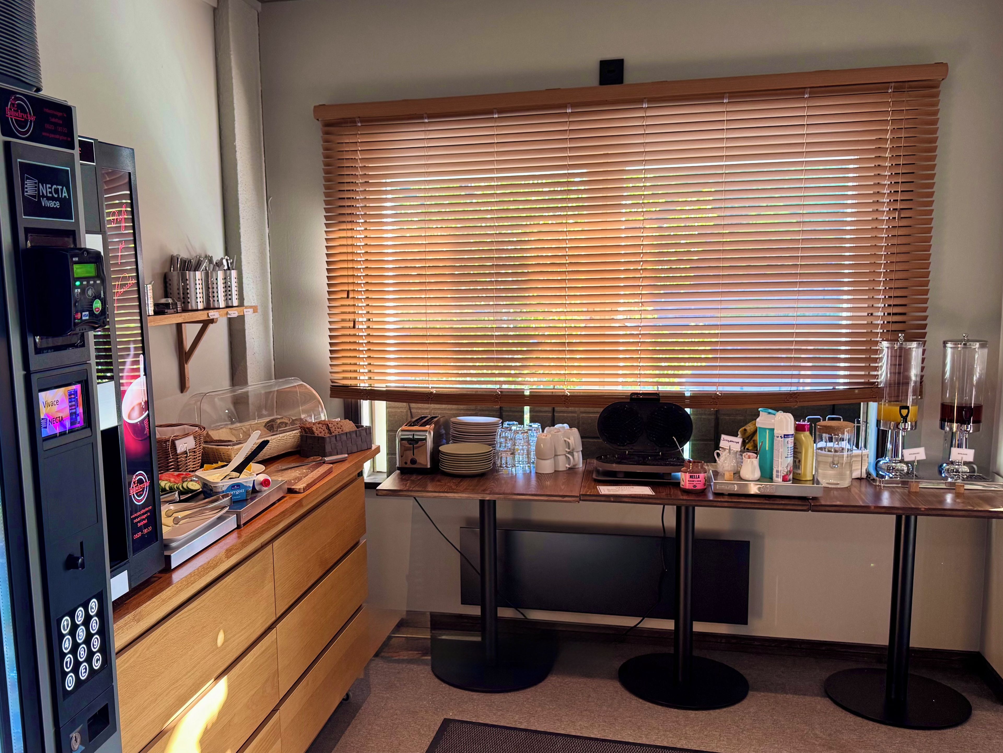 Una kitchenette con cafetera, tostadora y diversos utensilios de cocina sobre la encimera.