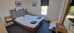 A room with a double bed, bedside tables, a desk with a chair, and a window. - Kramfors Stadshotell (Kramfors)