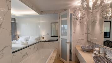 A modern bathroom with a large bathtub, two vessel sinks, and a mirror with a unique chandelier.