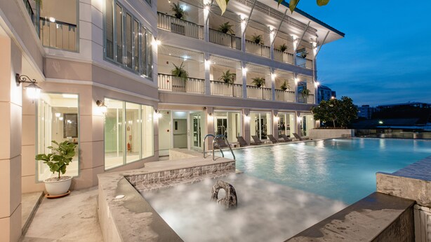 A multi-story hotel with a swimming pool, outdoor seating, and potted plants. - Siam Tharadol (Bangkok)