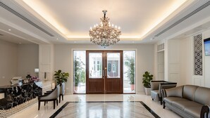 A spacious lobby with a marble floor, a large chandelier, a reception desk, and seating areas. - Siam Tharadol (Bangkok)