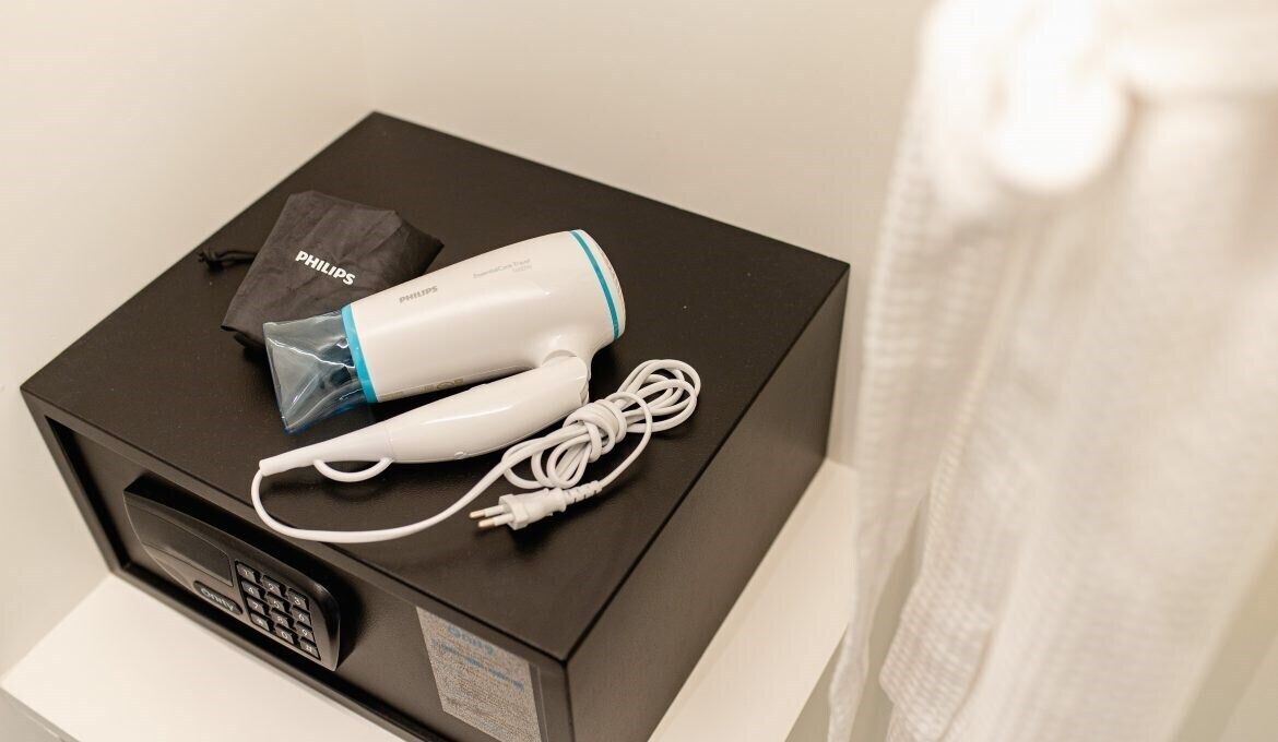 A Philips hair dryer and its accessories on a black box, likely a microwave, in a hotel room.