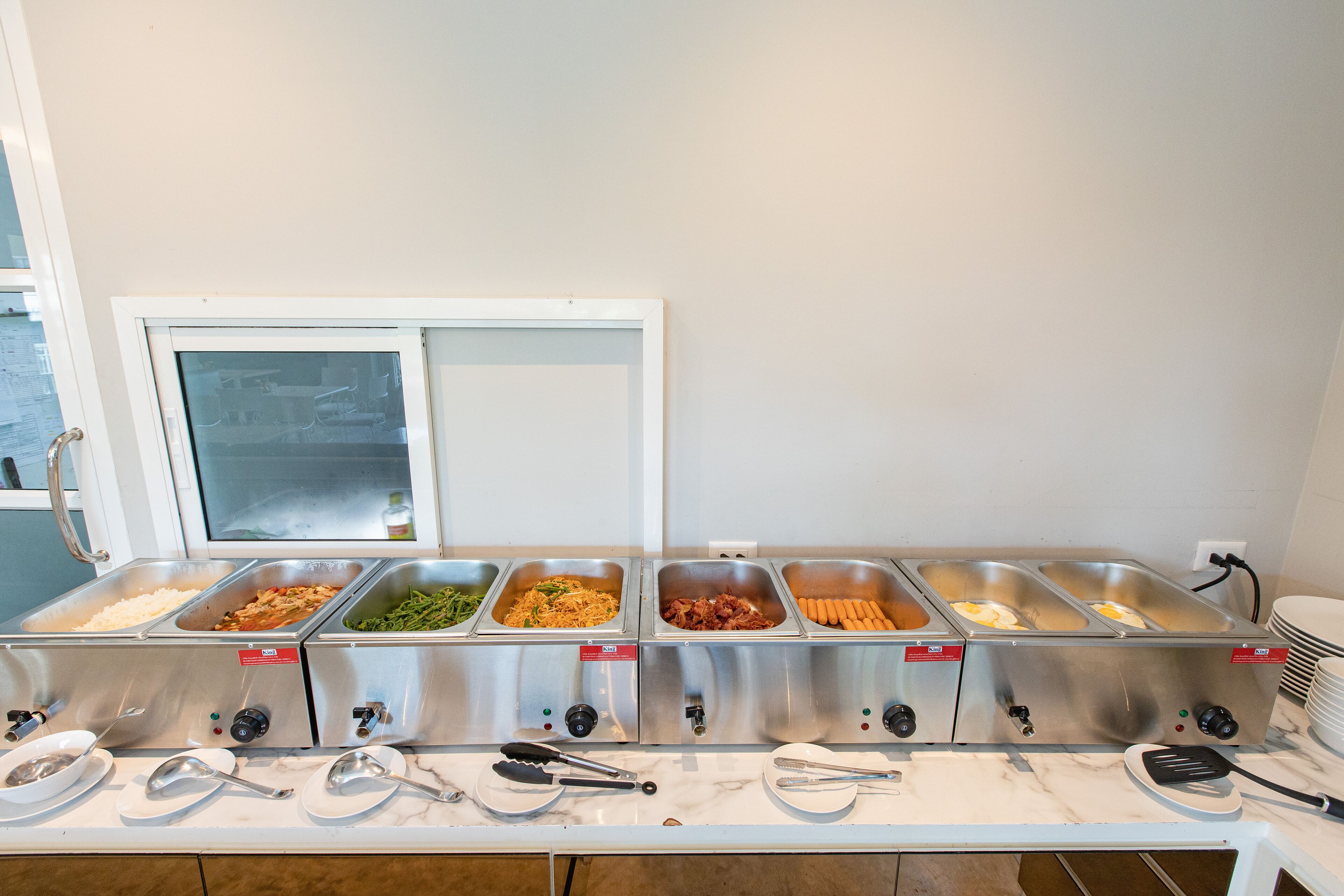 A buffet setup with multiple food dispensers and serving utensils.