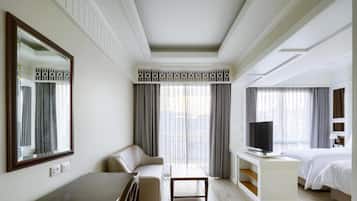 Una camera d'albergo con un letto grande, televisione, divano, scrivania e un ampio specchio.