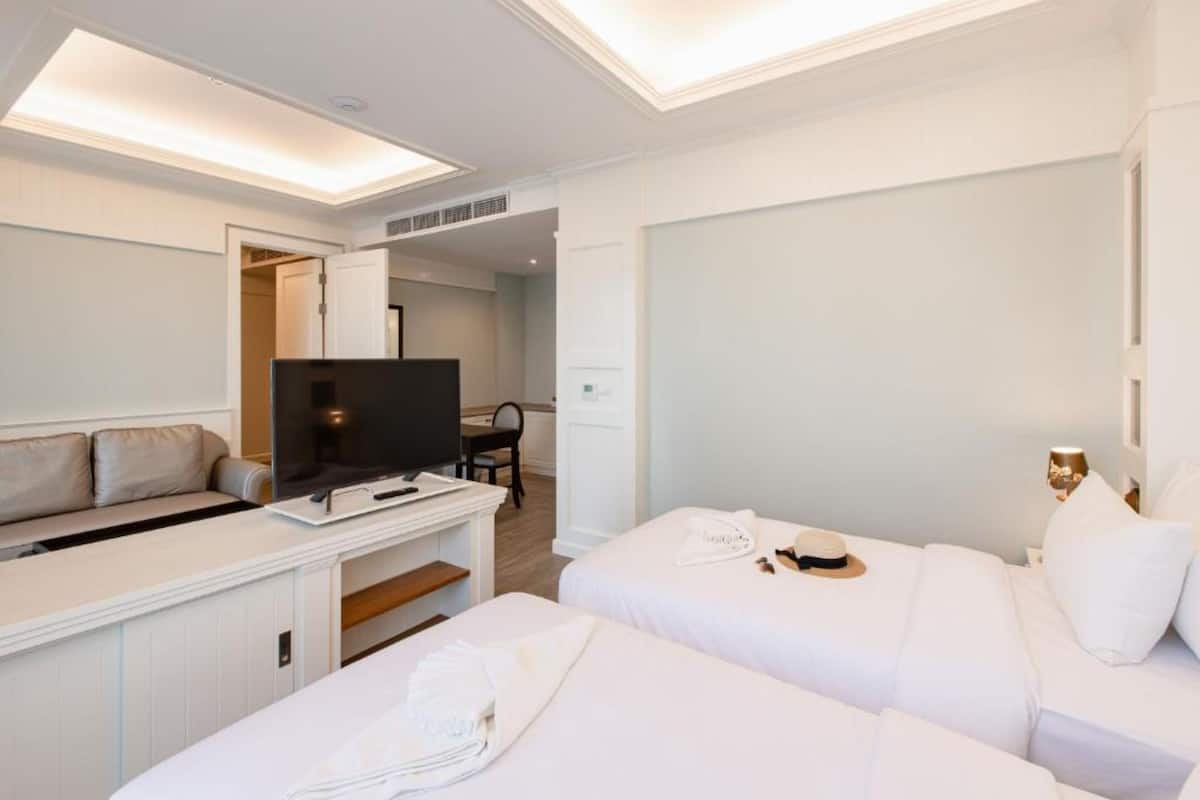 A hotel room with a bed, a desk with a TV, and a seating area.
