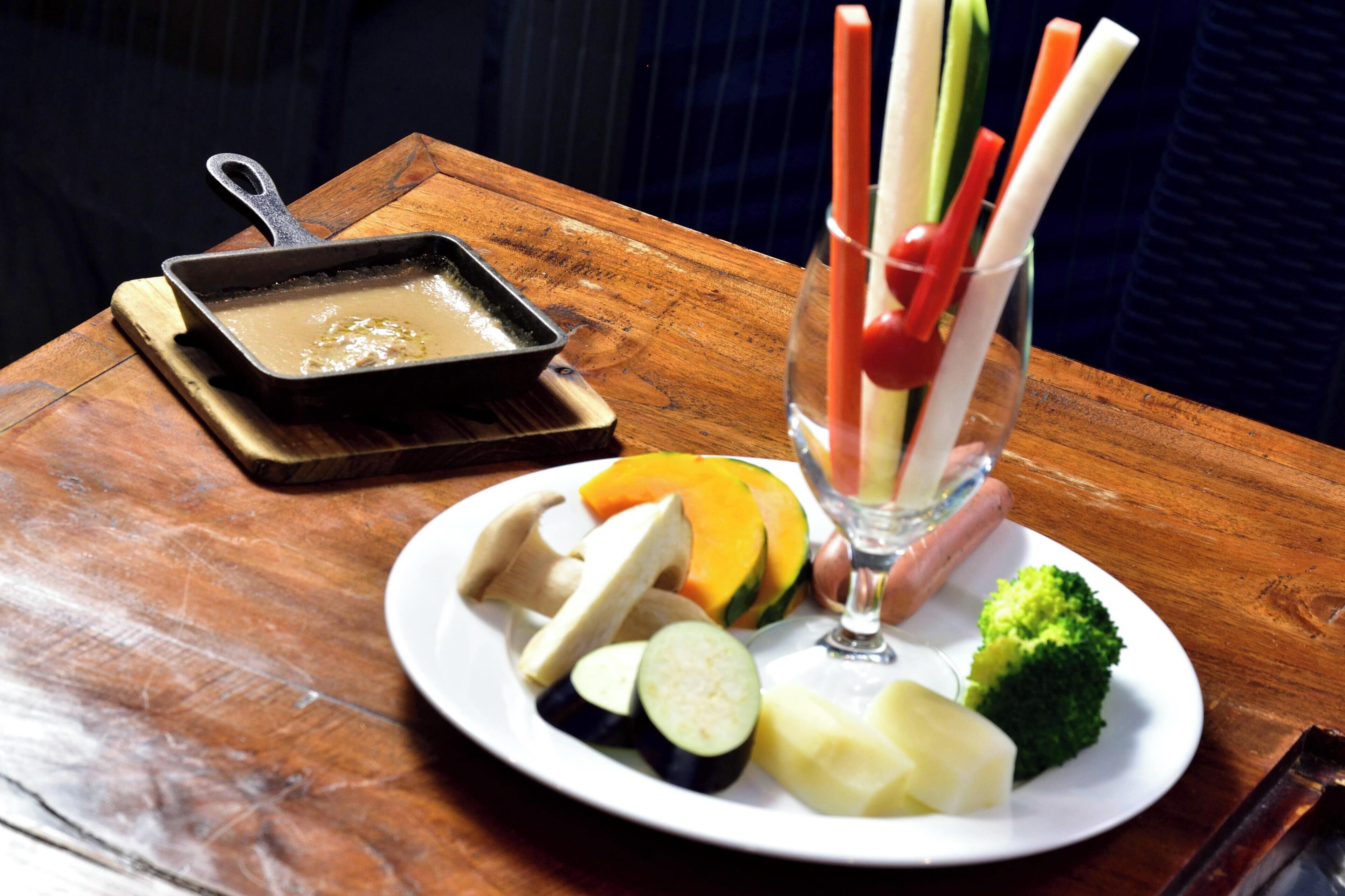 A plate of assorted vegetables and a glass of juice on a wooden table.